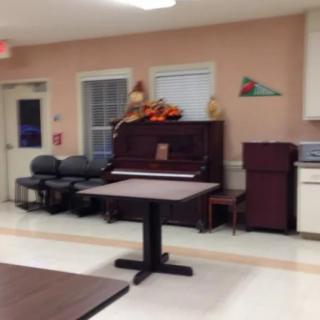 A room with a piano, chairs, and a table, decorated with seasonal items.