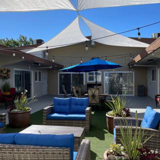 A sunny backyard patio with comfortable seating and shade sails.