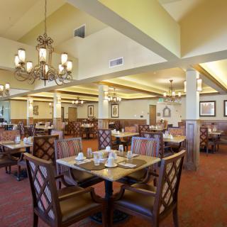 Spacious and elegantly decorated dining area with chandeliers and neatly set tables.