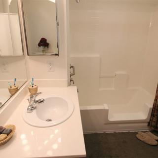 A clean white bathroom featuring a sink, mirror, and shower.