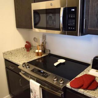 A modern kitchen with a stove, microwave, and stylish countertop.