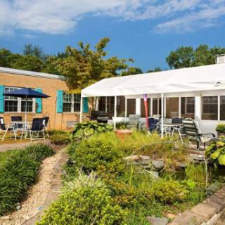 A beautiful outdoor space featuring a garden and patio seating under a clear blue sky.