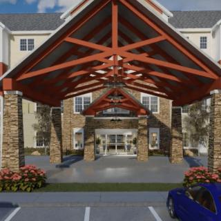 The image shows the entrance of a building with a large awning, parking area, and landscaped surroundings.