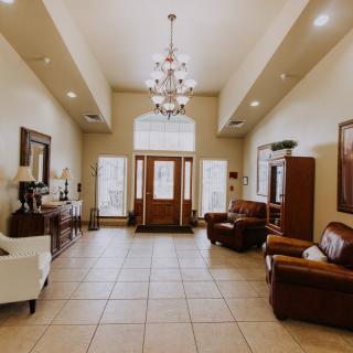 A spacious and elegantly designed living room featuring a chandelier, tiled flooring, and comfortable seating.