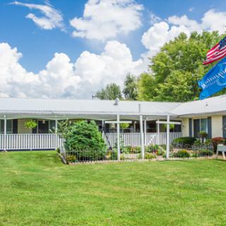 A charming residential home with a lush green lawn and flags flying under a picturesque cloudy sky.