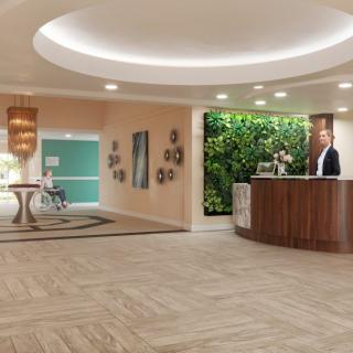 Modern hotel lobby with a reception desk and green wall.