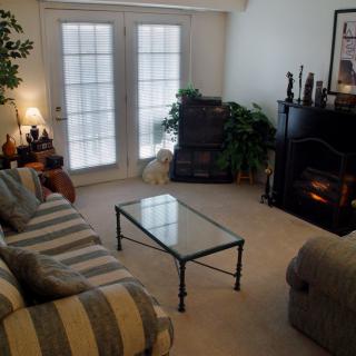 A cozy living room with a striped sofa, glass coffee table, and a fireplace.