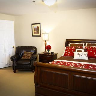 A cozy bedroom with a wooden bed, armchair, and stylish red accents.