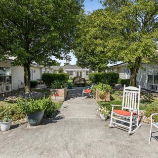 A peaceful courtyard with a pathway, surrounded by trees and seating areas.