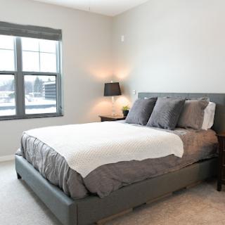A modern and cozy bedroom featuring a stylish gray bed and soft lighting.
