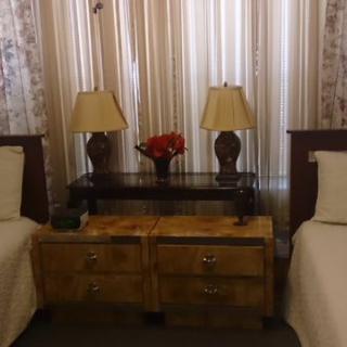 A cozy bedroom with twin beds, a shared nightstand, and decorative table lamps.