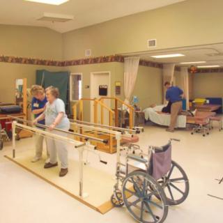 A physical therapy session in progress, with patients and therapists in a rehabilitation facility.