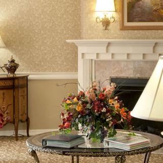 A cozy living room with elegant decor, featuring a table with a floral arrangement and a fireplace.
