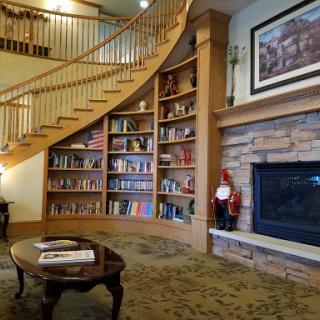 A cozy library space featuring a spiral staircase, extensive bookshelves, and a warm fireplace.