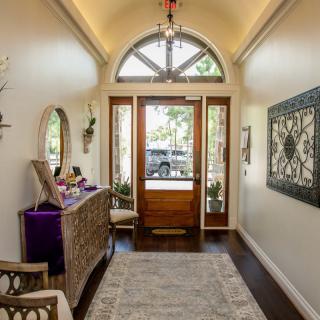 A well-designed foyer featuring a console table with decor, a decorative mirror, and wall art, leading out to a wooden front door with glass panels.