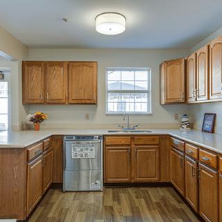 A modern kitchen with wooden cabinets and a dishwasher, featuring ample counter space and natural light from the window.