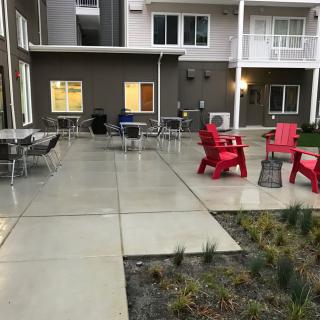 A modern outdoor patio with red chairs and tables in a residential complex.