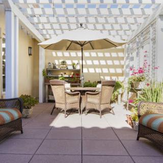 A cozy patio setup featuring comfortable seating, an umbrella for shade, and vibrant flowers.
