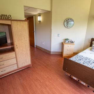 A well-furnished bedroom featuring a comfortable bed, a television unit, and warm wooden accents.