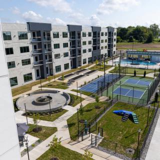 A modern apartment complex featuring tennis courts and landscaped outdoor areas.