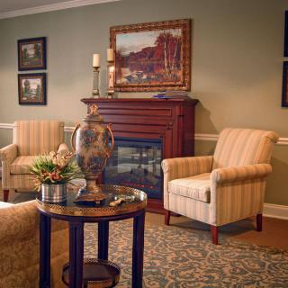 A cozy living room with a traditional fireplace, armchairs, and elegant decor.