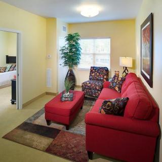 A cozy living room featuring a red sofa, decorative rug, and stylish furniture.