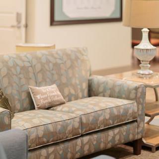A cozy living room setup featuring a patterned sofa, side table with a lamp, and decorative cushions.