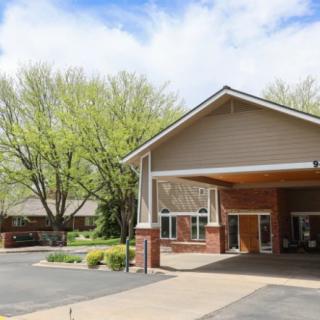 A building entrance with a driveway, surrounded by trees and clear skies.