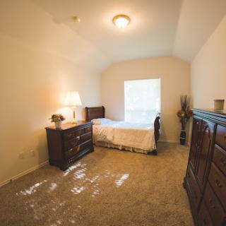 A cozy and well-lit bedroom featuring a bed, dresser, and tasteful decor.