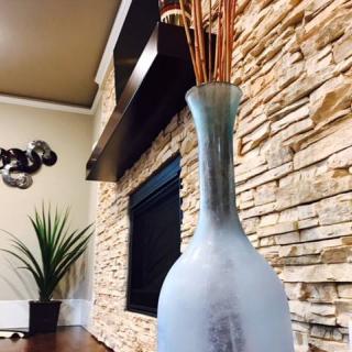 A modern interior featuring a frosted vase and stone fireplace.