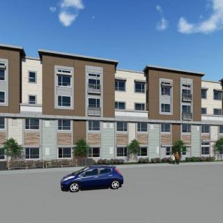 A modern apartment complex with a car parked on the street.