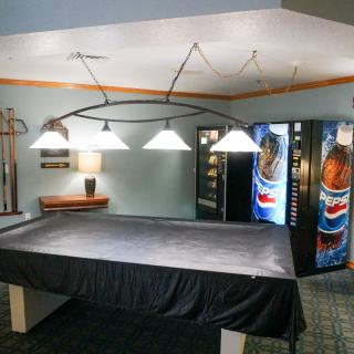 A recreation area featuring a covered pool table and vending machines with overhead lights.