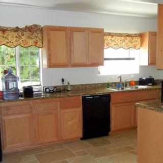 A spacious kitchen with wooden cabinets, granite countertops, and modern appliances.