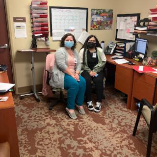 Two healthcare professionals seated in an office, both wearing masks.