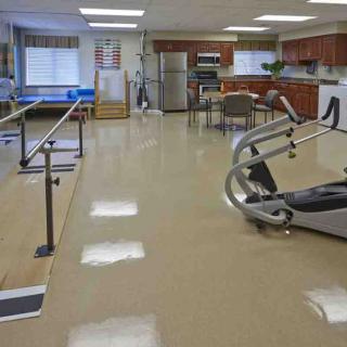 A rehabilitation room equipped with exercise machines and parallel bars for physical therapy.