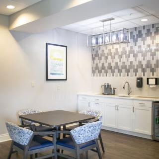 A modern kitchen area with a dining table, chairs, and stylish backsplash.