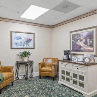 A cozy waiting room with comfortable seating, art on the walls, and a coffee station.
