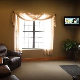 A cozy waiting room with a sofa, window, television, and a plant.