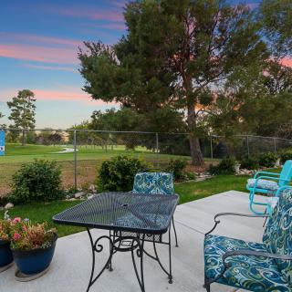 A patio with outdoor furniture overlooking a garden during sunset.
