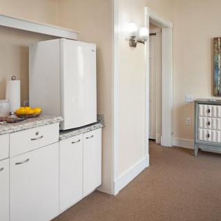 A well-organized kitchen area with modern appliances and cabinets, featuring a bowl of fruit on the countertop.