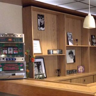 A vintage-themed interior featuring a jukebox and wooden shelves adorned with various photographs and memorabilia.