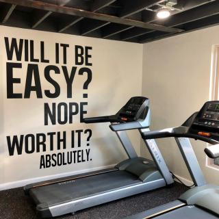 Home gym with motivational wall art and treadmills.