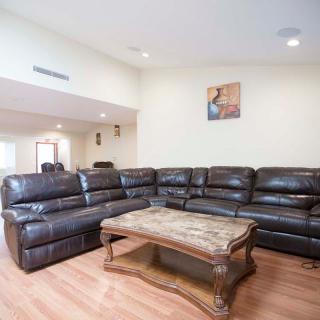 A spacious living room with a large sectional sofa and a wooden coffee table on hardwood floors.