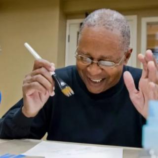 A person happily painting with a brush, enjoying a creative activity.