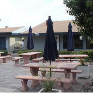 A patio area with tables, benches, and umbrellas in front of a building.