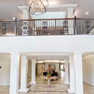 A spacious and elegantly designed lobby featuring a modern chandelier and symmetrical columns.