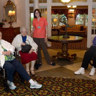 A group of people relaxing in a cozy indoor setting, some seated and one standing, enjoying a social moment.