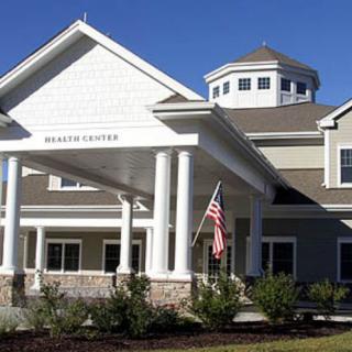 An exterior view of a health center with classic architectural features, including columns and an American flag at the entrance.