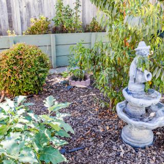 A serene garden with a small fountain statue surrounded by lush greenery.