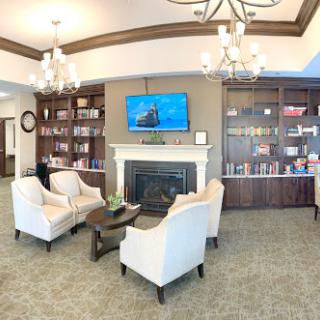 A cozy and inviting living room area featuring comfortable chairs, a fireplace, and shelves filled with books.